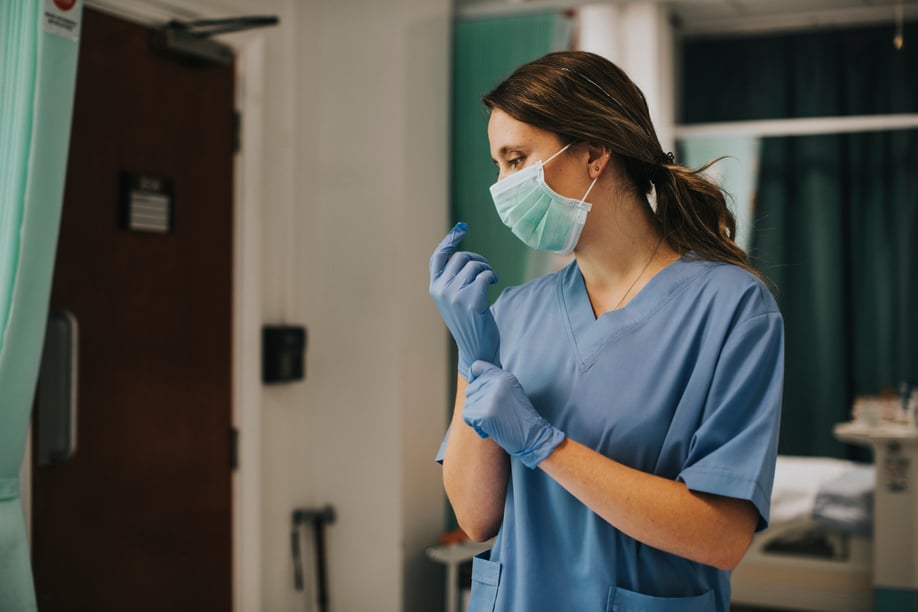 Public health nurse putting on gloves for patient care
