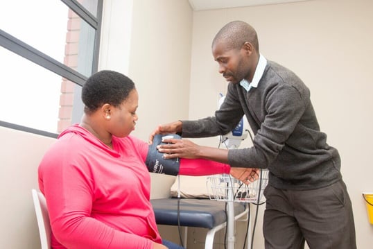 Health worker taking blood pressure of patient